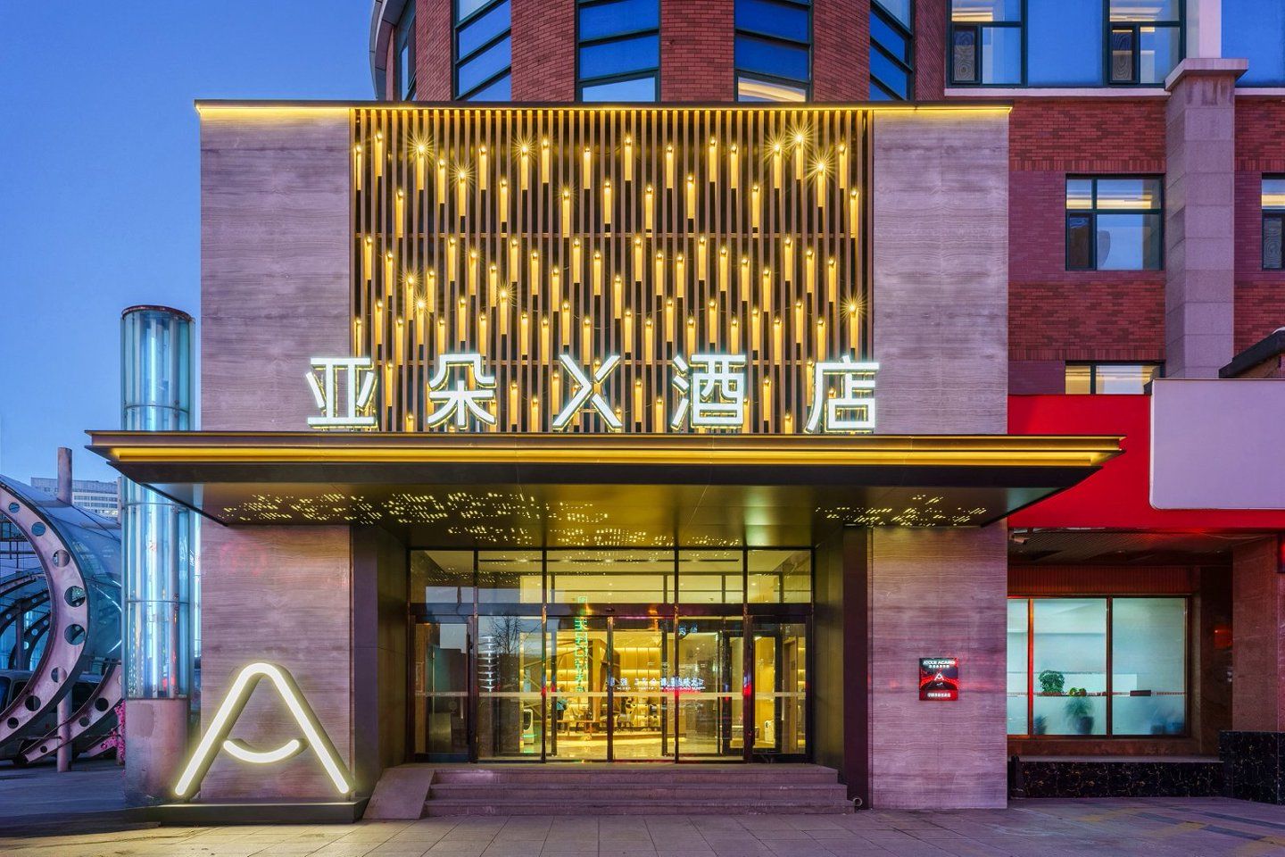 A hotel entrance with illuminated signage, a modern facade, and a prominent entrance.