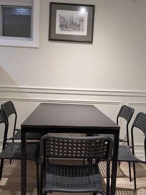 A dining area with a table and four chairs, a framed picture on the wall, and a window with a view of buildings. - Nice cozy Bedroom with ensuite bathroom in Downtown Cooksville, Mississauga (Mississauga)