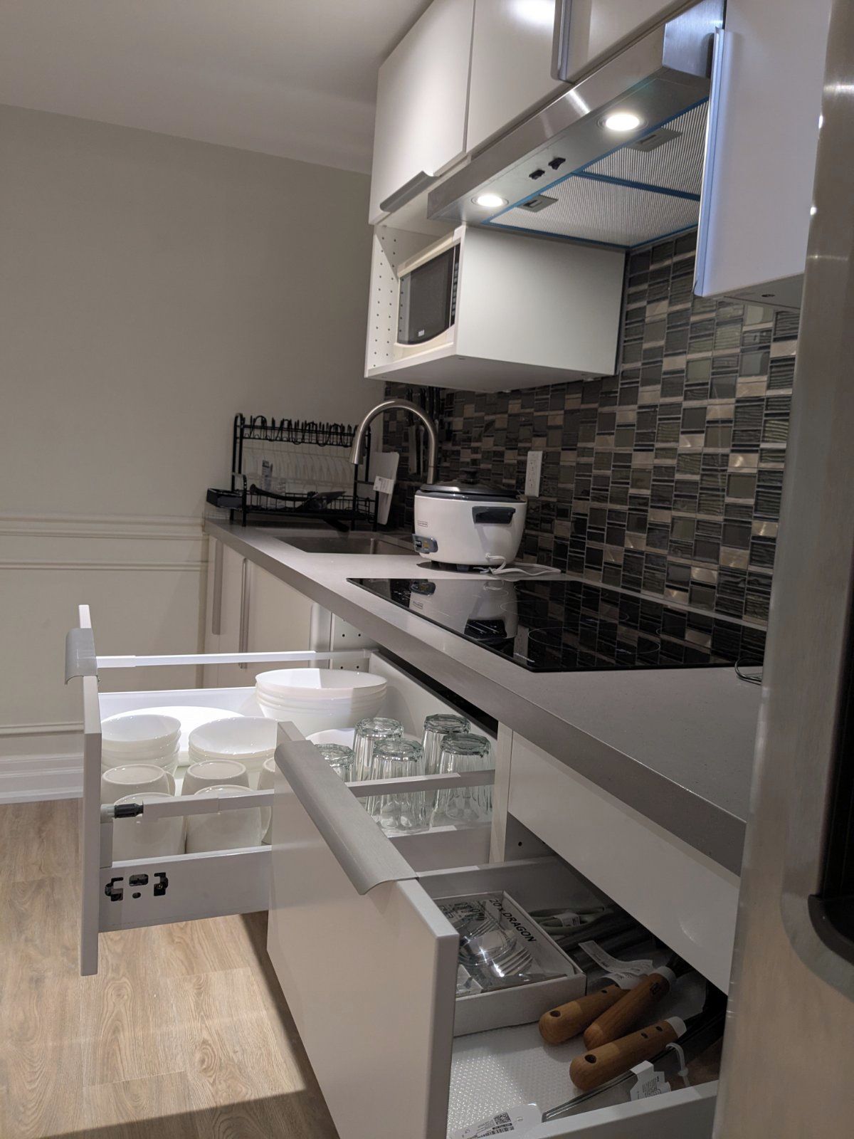 A modern kitchen with white cabinetry, a microwave, and a tiled backsplash.