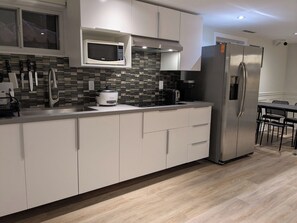 A modern kitchen with white cabinets, a stainless steel refrigerator, a microwave, and a toaster. - Nice cozy Bedroom with ensuite bathroom in Downtown Cooksville, Mississauga (Mississauga)
