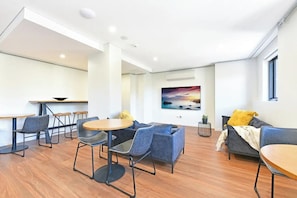 A modern interior with a dining area, seating, and a large painting on the wall. - Modern Fully Furnished Studio Kingsford (Kingsford)