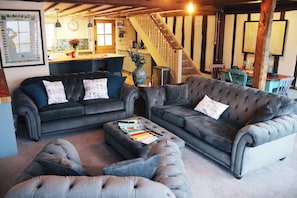 A living room with two sofas, a coffee table, and a staircase. - Chinnerys Country Cottage (Cavendish)