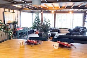 A cozy room with a wooden dining table, two chairs, a Christmas tree, and a large window. - Chinnerys Country Cottage (Cavendish)