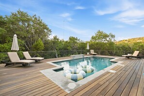 A pool area with wooden decking, lounge chairs, and a hot tub. - Toro Haus: Secluded Pool & Pickleball Paradise (Austin)