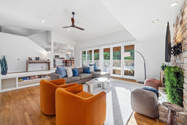A spacious living room with a sofa, orange armchairs, and a coffee table.