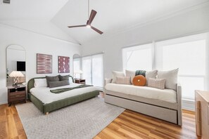 A modern bedroom with a bed, sofa, and a ceiling fan. - Toro Haus: Secluded Pool & Pickleball Paradise (Austin)