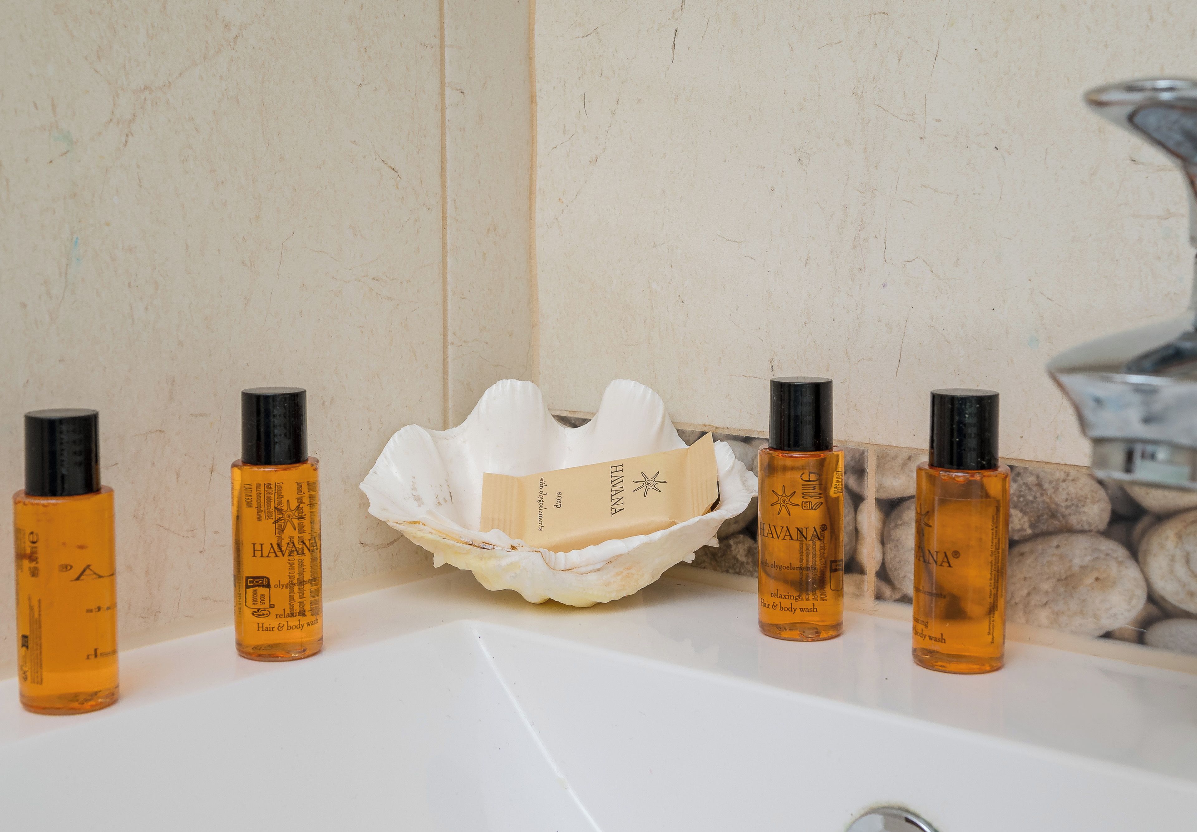 A bathroom sink with five bottles of Havana body wash and a soap dish.