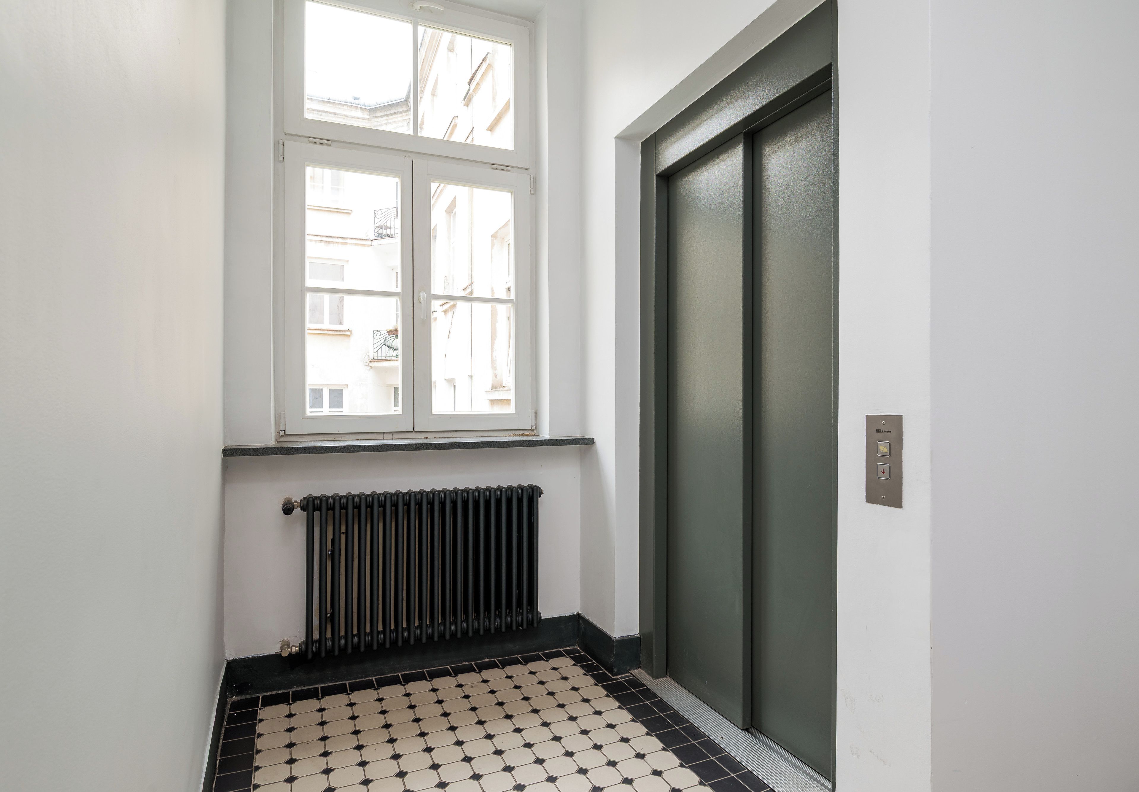 A room with a radiator, a window, and a door.