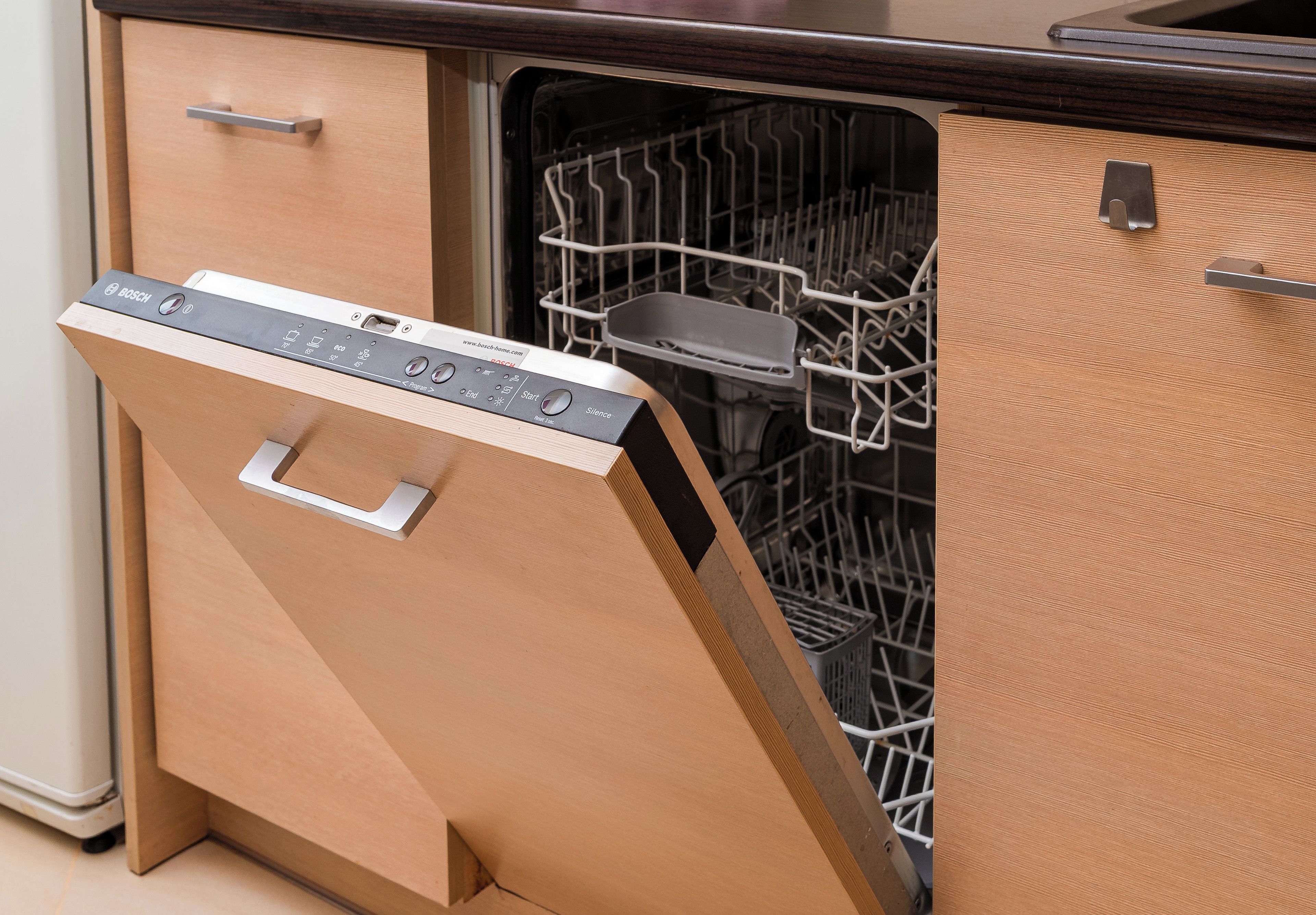 A kitchen with a dishwasher and a wooden cabinet.
