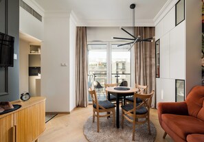 Una sala de estar moderna con una mesa redonda, sillas, un sofá y una televisión.