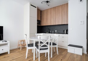 Eine kompakte Küche mit weißen Schränken, einer schwarzen Arbeitsplatte und einem Holzboden.