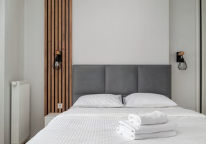 Habitació d'hotel moderna amb un llit gran, dues taules de nit, una paret decorativa de fusta i un radiador.