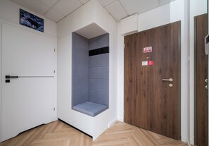 Habitació d'hotel amb una banca integrada, una porta de fusta i un lluminari al sostre.