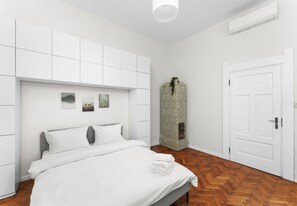 Een moderne slaapkamer met een bed, een witte inbouwkast en een decoratieve zuil.
