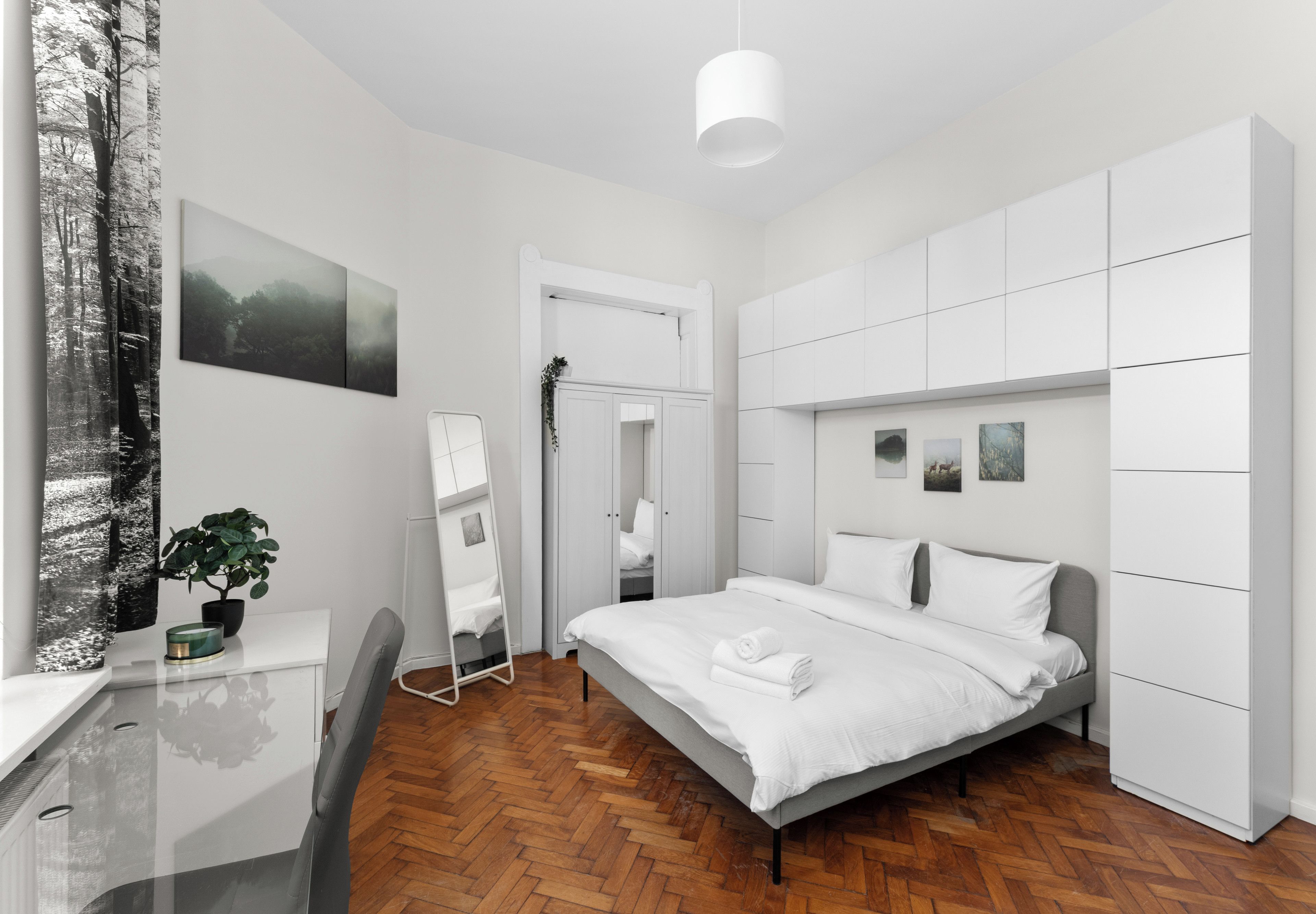 Een moderne slaapkamer met een bed, bureau en garderobe.