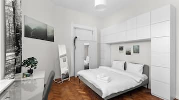 Een moderne slaapkamer met een bed, bureau en garderobe.