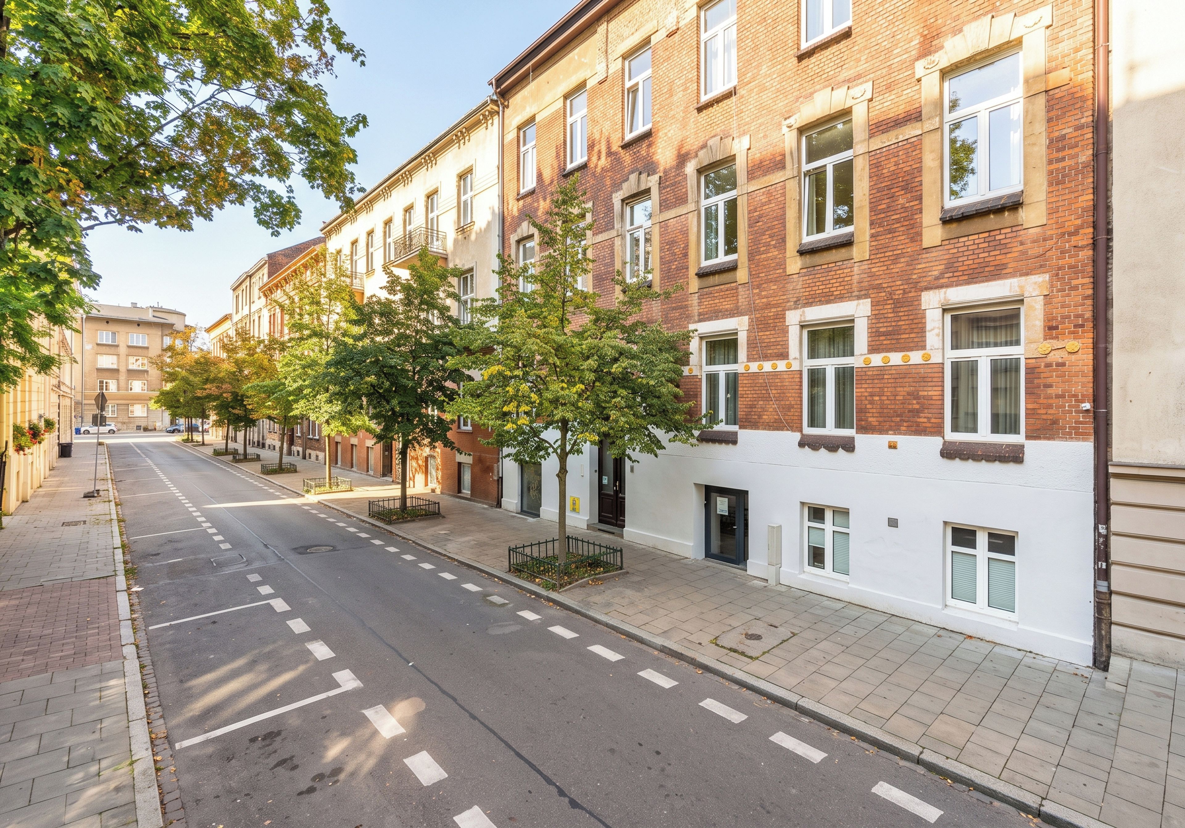 Een straat met hoge gebouwen, met een duidelijke weg met wegmarkeringen en trottoirs.
