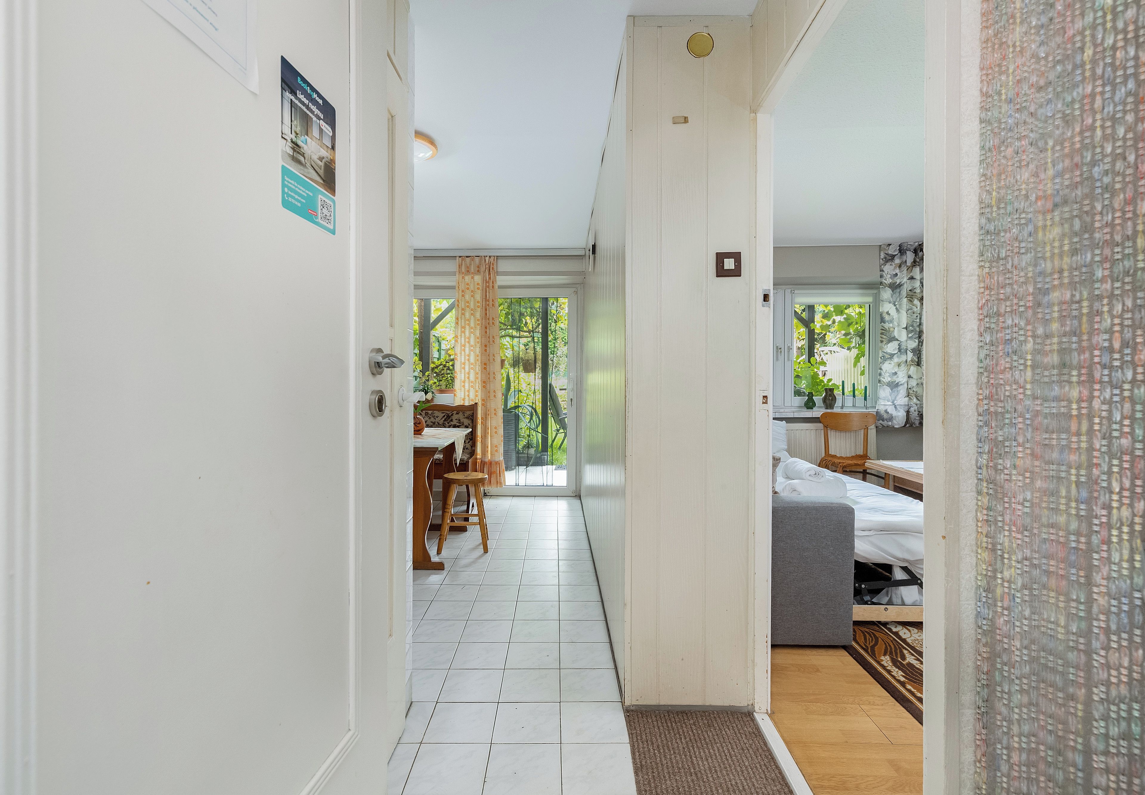 A hallway leading to a bedroom with a bed, a chair, and a table.