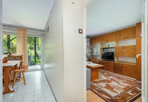 A room with a dining area, a kitchen with wooden cabinets, and a patterned rug. - Piaskowa 57 Homely Apartment (Police)