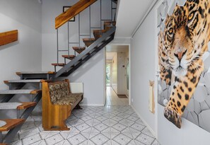 Een trap met houten treden en een modern ontwerp, een gestreept bankje en een muur met een groot dierenprint.
