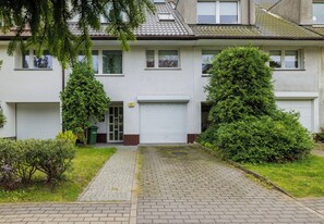 Een woonhuis met twee verdiepingen en een geplaveid pad dat naar een garage leidt.