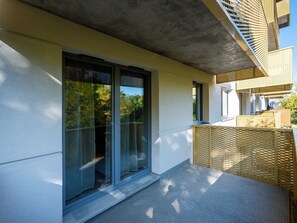 Ein modernes Gebäude mit großen Schiebeglastüren, einer Betondecke und einem Holzbalkon.