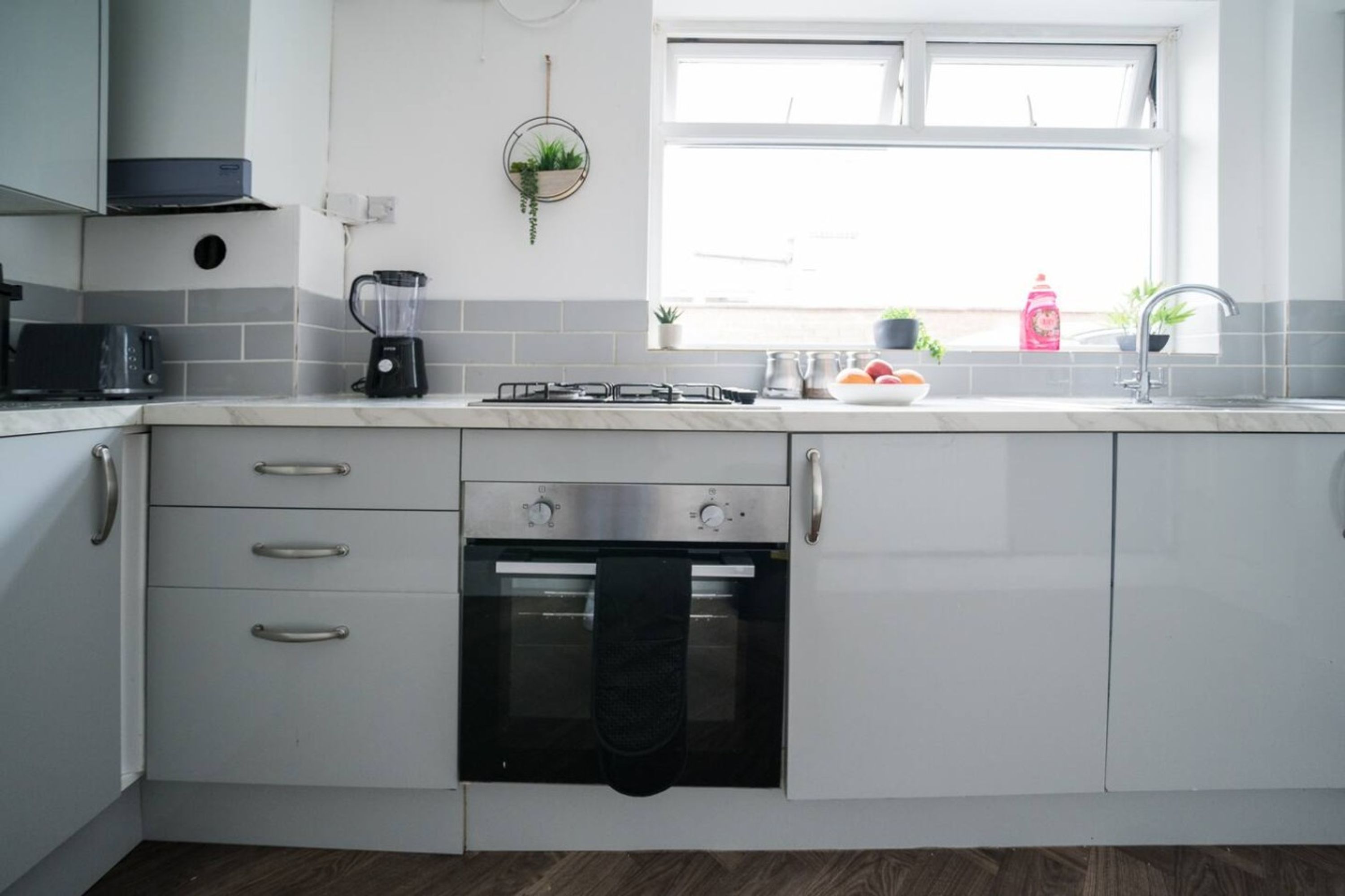 Eine moderne Küche mit integriertem Backofen, einem Gasherd, einem Toaster und einem Mixer.