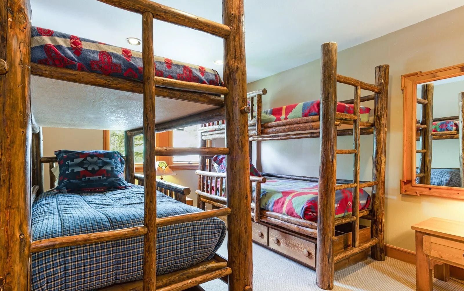 A room with bunk beds, a wooden desk, and a mirror.