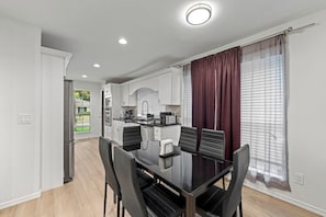 A modern kitchen with white cabinets, a black dining table, and chairs. - Prime Location | Pool | Game Room | King Bed (Plano)