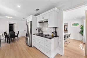 A modern kitchen with white cabinetry, a stainless steel refrigerator, and a black countertop. - Prime Location | Pool | Game Room | King Bed (Plano)