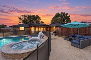 Un jardin avec une piscine, un jacuzzi et du mobilier d’extérieur.