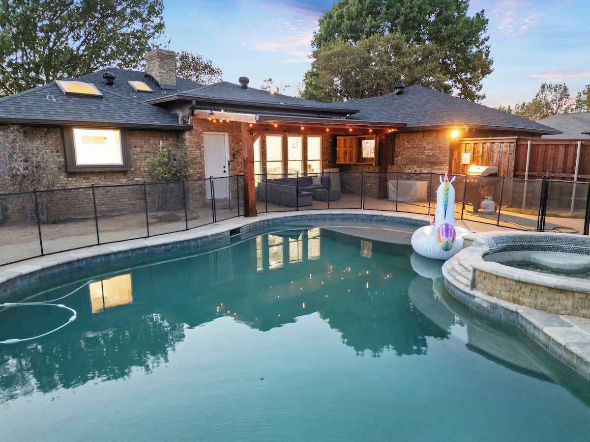 A backyard with a swimming pool, a hot tub, and a covered patio area.