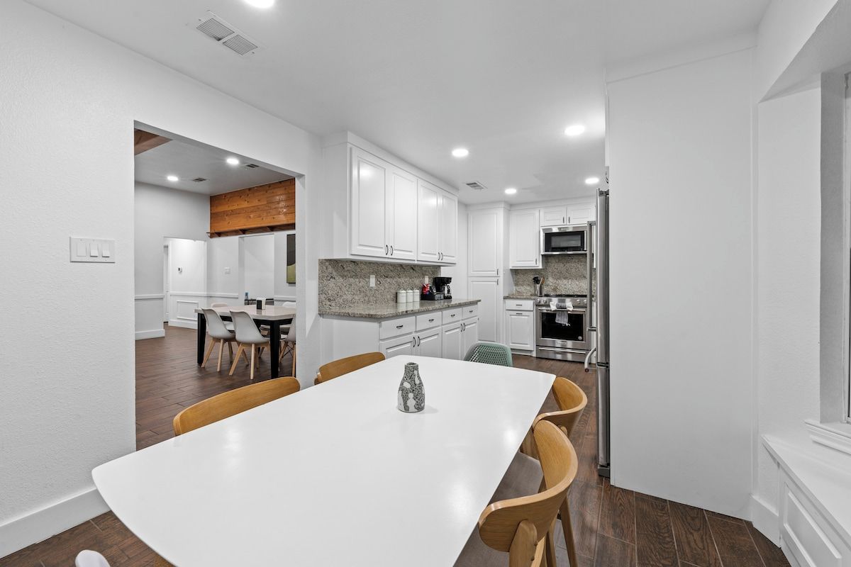 A modern kitchen with white cabinets, a granite countertop, and stainless steel appliances.