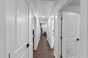 Un couloir avec des portes blanches, un plancher en bois et un luminaire au plafond.