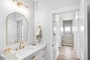 A modern bathroom with a large mirror, dual sinks, and a vanity with drawers. - Luxe 6BR Heated Pool | 200 Ft to Beach | Sleeps 20 (gulf shores)
