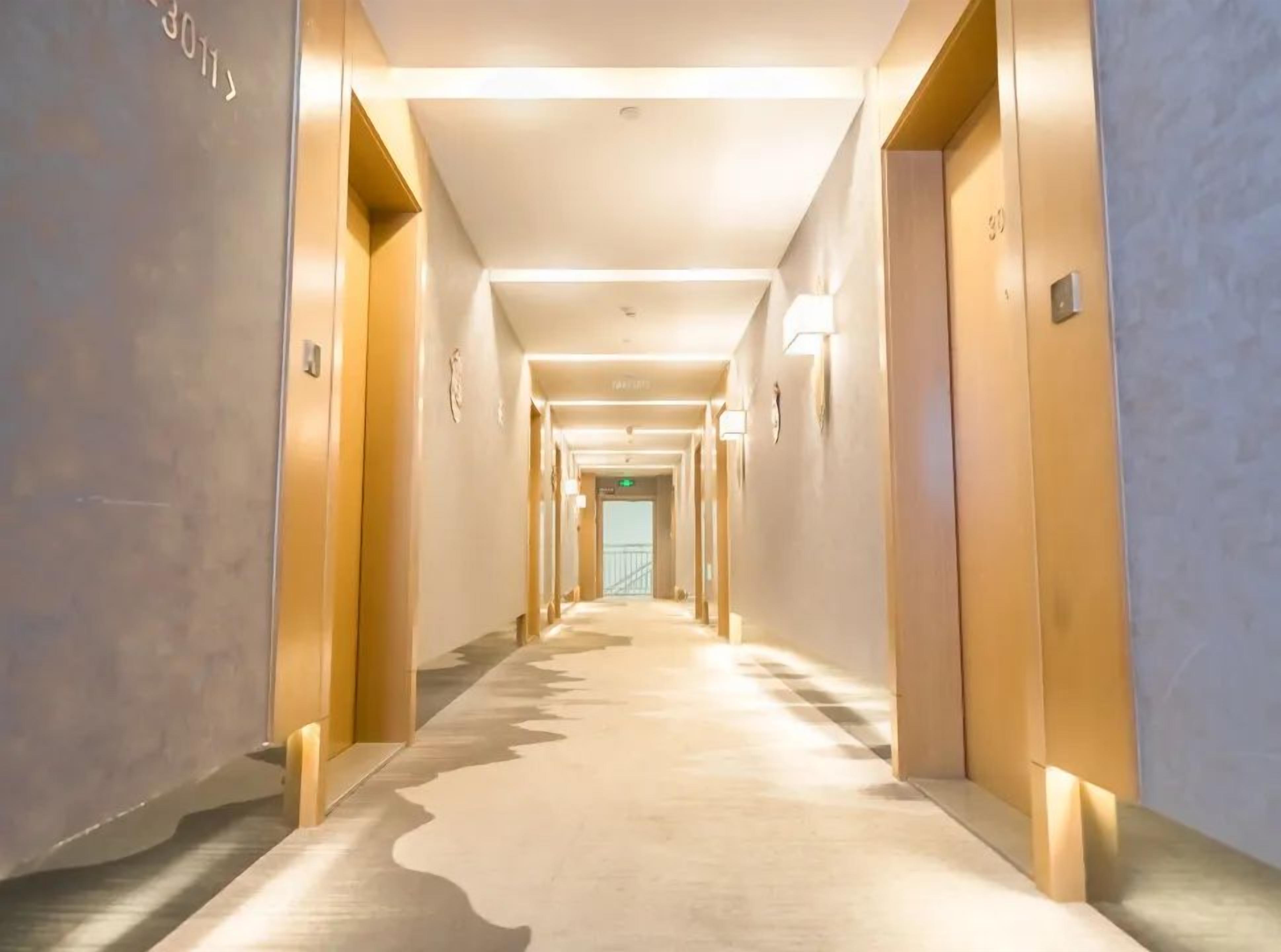 Ein Hotelgang mit Türen an beiden Seiten, einem Teppichboden und Deckenleuchten.