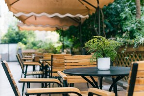 Outdoor seating with tables and chairs, a potted plant, and a wooden fence. - Yunfuli Hotel Long'an Station (Chengdu)