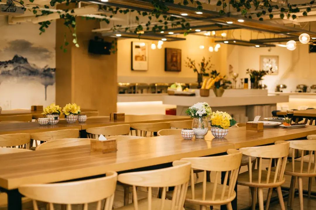 Un restaurante con mesas y sillas de madera, decorado con flores amarillas.