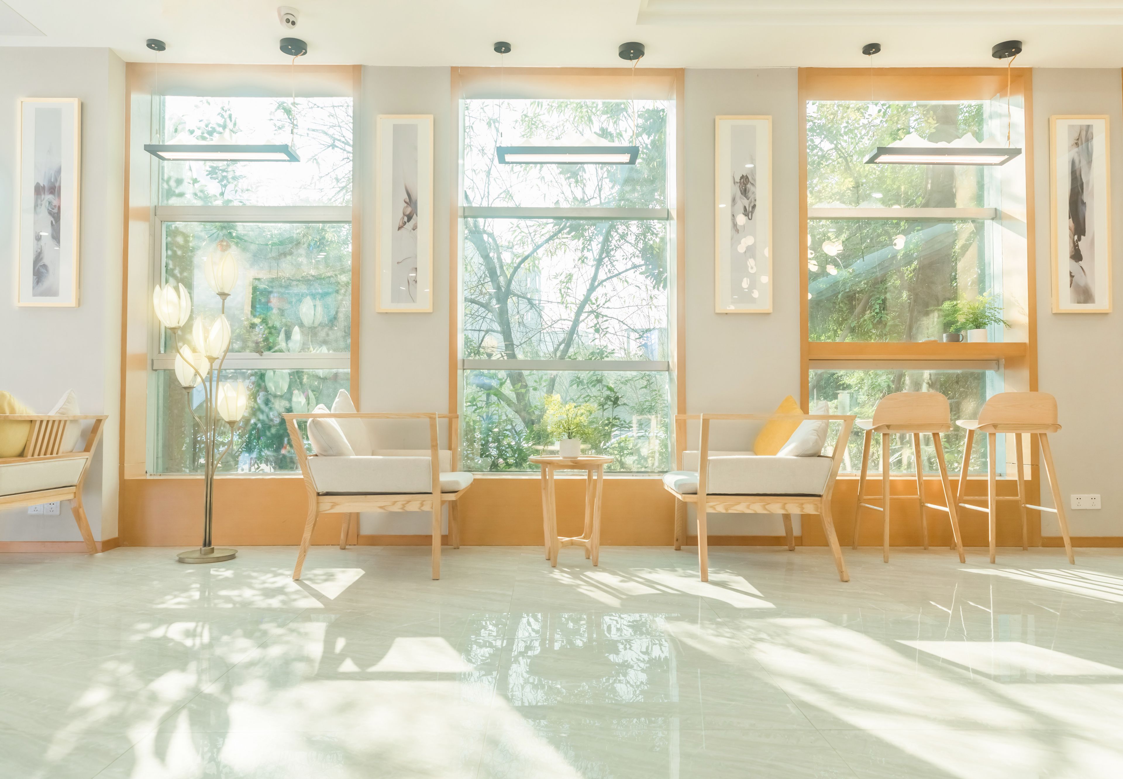 A modern room with large windows, a sofa, chairs, and a floor lamp.