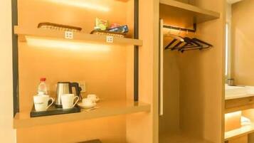 A compact room with built-in shelving, a small refrigerator, and a plant.