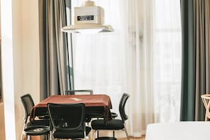 A hotel room with a dining table, chairs, a bed, and a window with curtains. - Yunfuli Hotel Long'an Station (Chengdu)