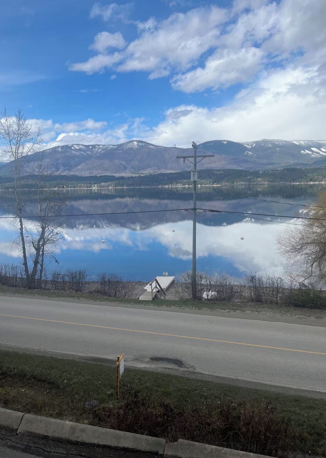A road with a clear view of a lake and mountains in the distance.