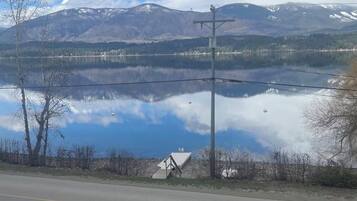 A road with a clear view of a lake and mountains in the distance.