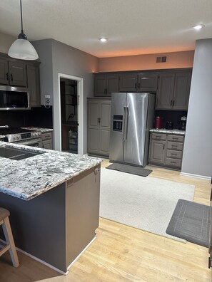 A modern kitchen with a central island, stainless steel appliances, and a pendant light. - Excellent 5-bed room close to airport & downtown in charming Kansas City suburb (Kansas City)