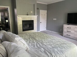 A bedroom with a bed, a fireplace, a dresser, and a television. - Excellent 5-bed room close to airport & downtown in charming Kansas City suburb (Kansas City)