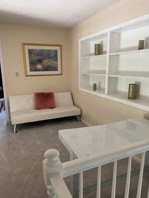 A room with a white sofa, a glass coffee table, and a white shelving unit against the wall. - Excellent 5-bed room close to airport & downtown in charming Kansas City suburb (Kansas City)