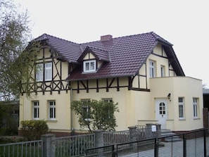 Ein zweistöckiges Gebäude mit Satteldach und einer Mischung aus Fachwerkkonstruktion und verputzten Wänden.