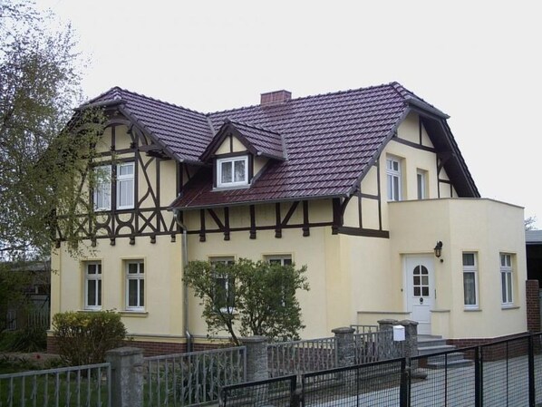 A two-story building with a gabled roof and a mix of timber framing and plaster walls. - mit zwei Doppel- und einem Einzelzimmer, Essküche, Vollbad und Balkon by Interhome (Küstriner Vorland)