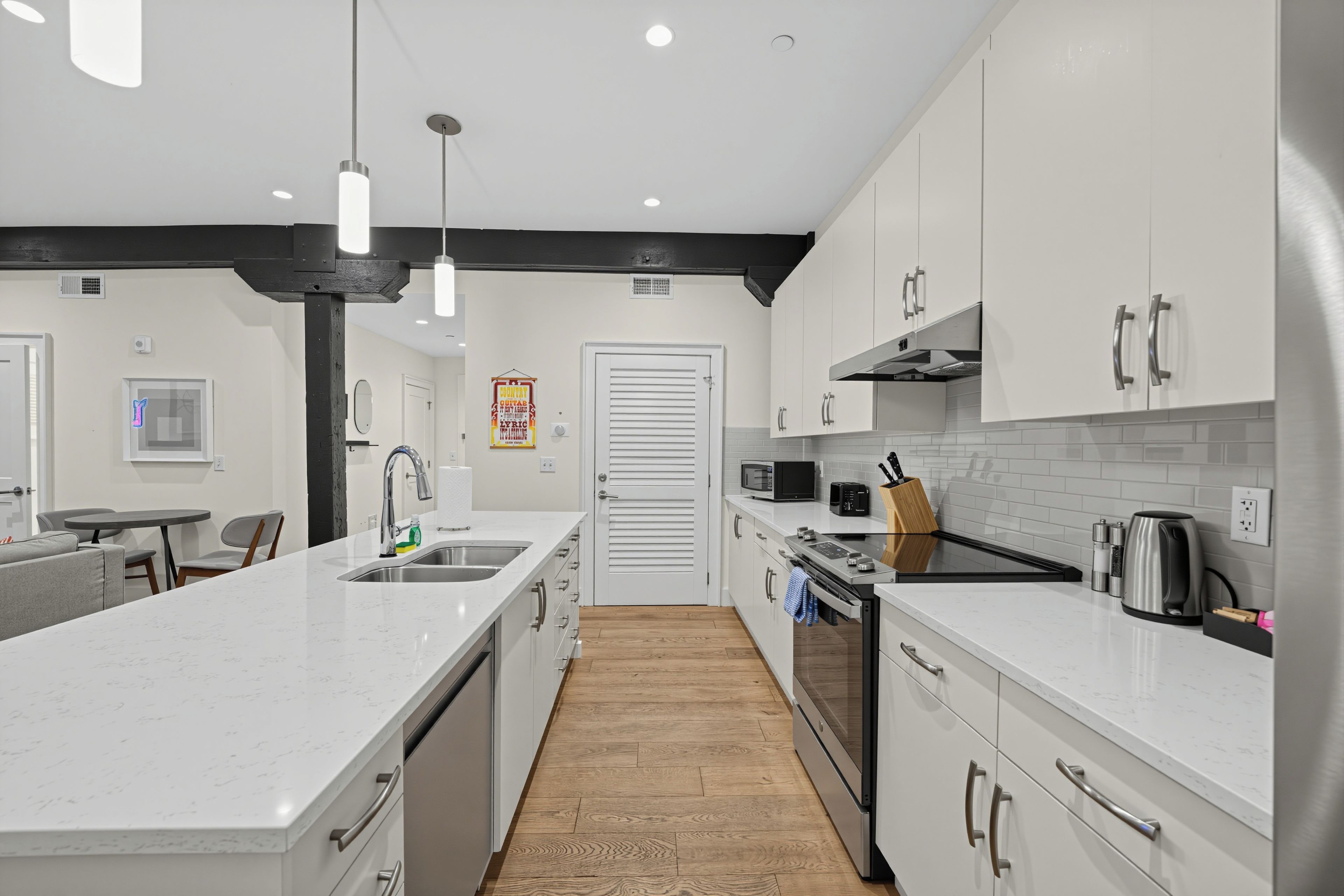 A modern kitchen with white cabinetry, stainless steel appliances, and a central island.