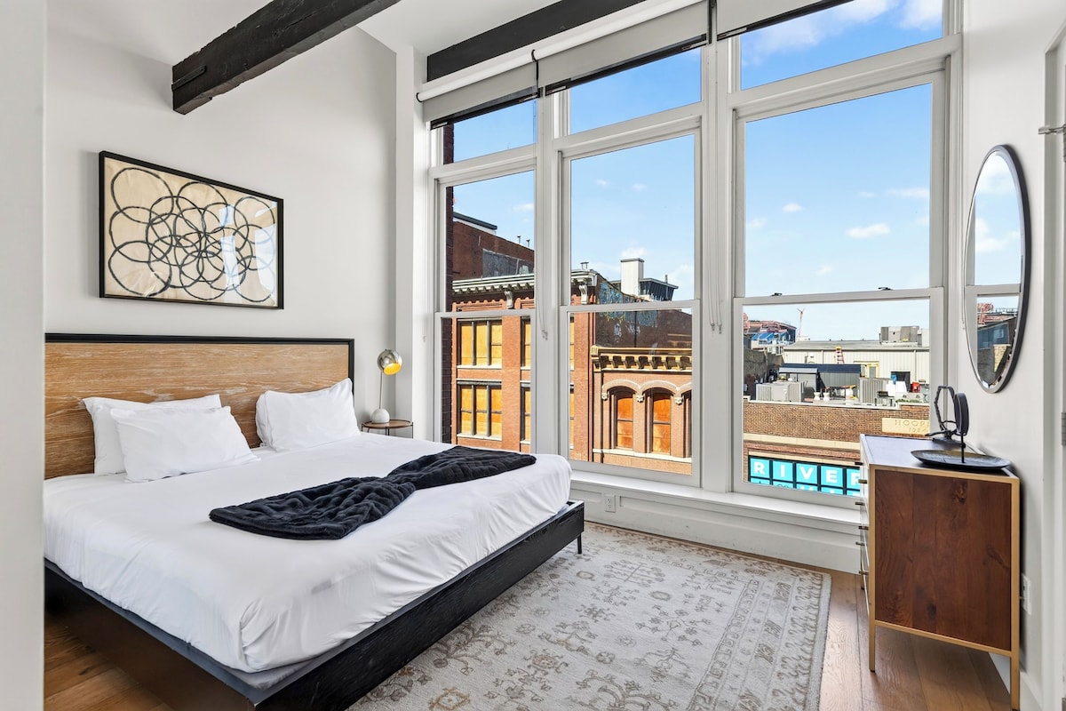 Un dormitorio con una cama grande, vistas de la ciudad a través de amplias ventanas y un diseño moderno.